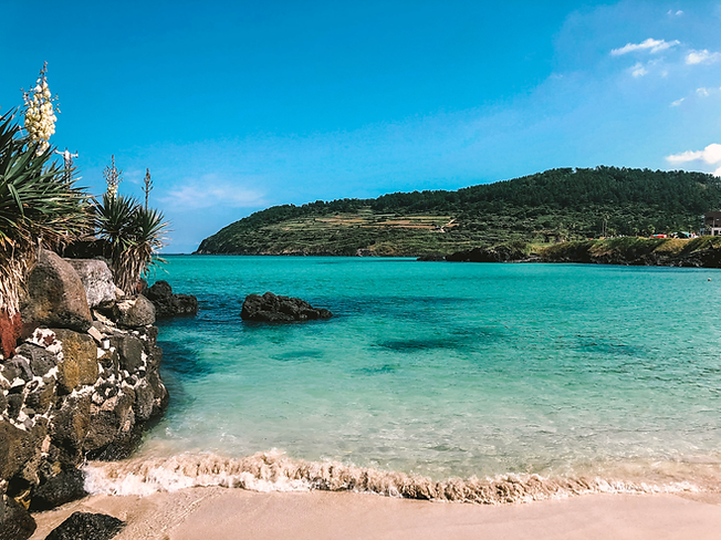 A beach with rocks and water Description automatically generated