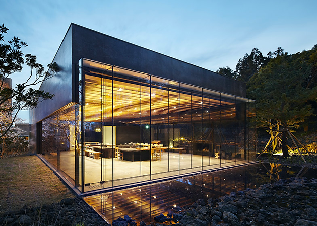 A building with glass walls and a large area with trees Description automatically generated